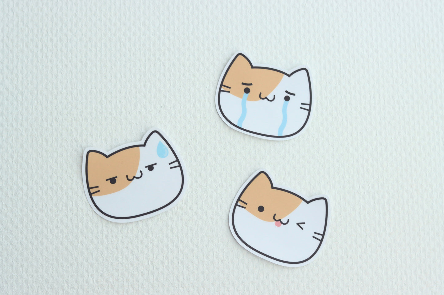 A collection of 3 cat emoji stickers with different expressions