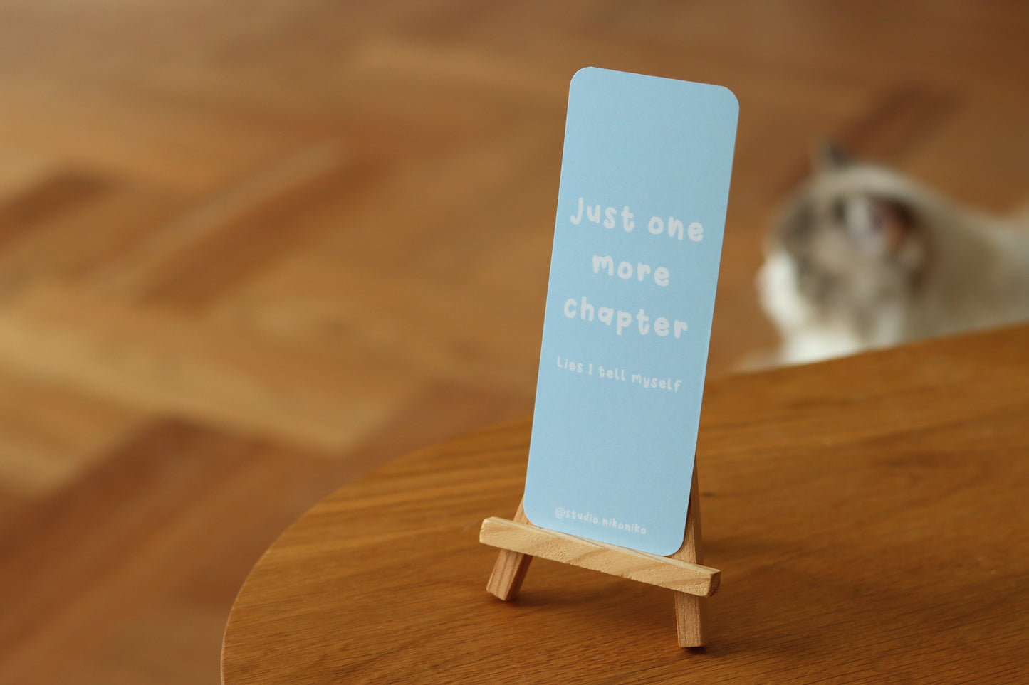 One blue bookmark with the text: Just one more chapter standing on a wooden table
