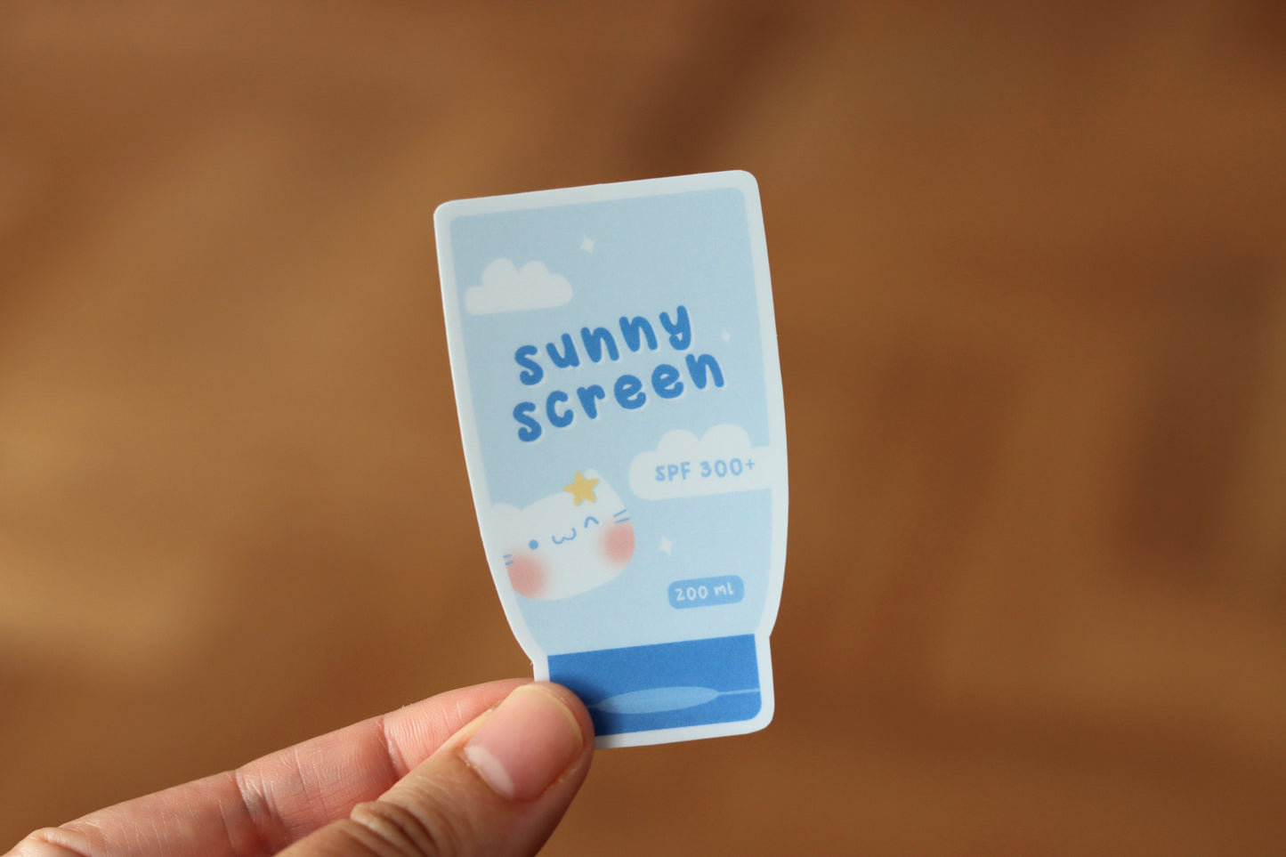 Hand holding a blue sunscreen sticker called: sunny screen